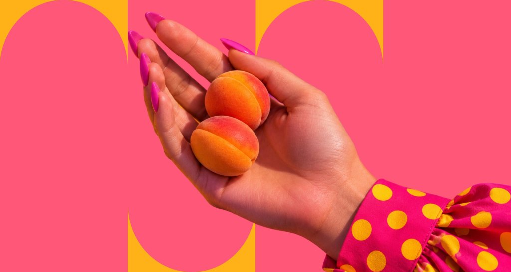 Mano femminile che contiene due albicocche come metafora del seno piccolo